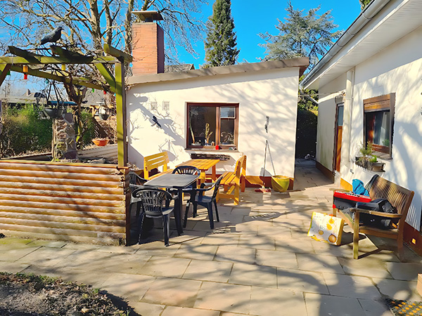 Wohnen auf Zeit – Außenbereich – Gepflegter Gartenbereich mit Terrasse, Sitzgruppe, Holzabtrennung und sonniger Atmosphäre